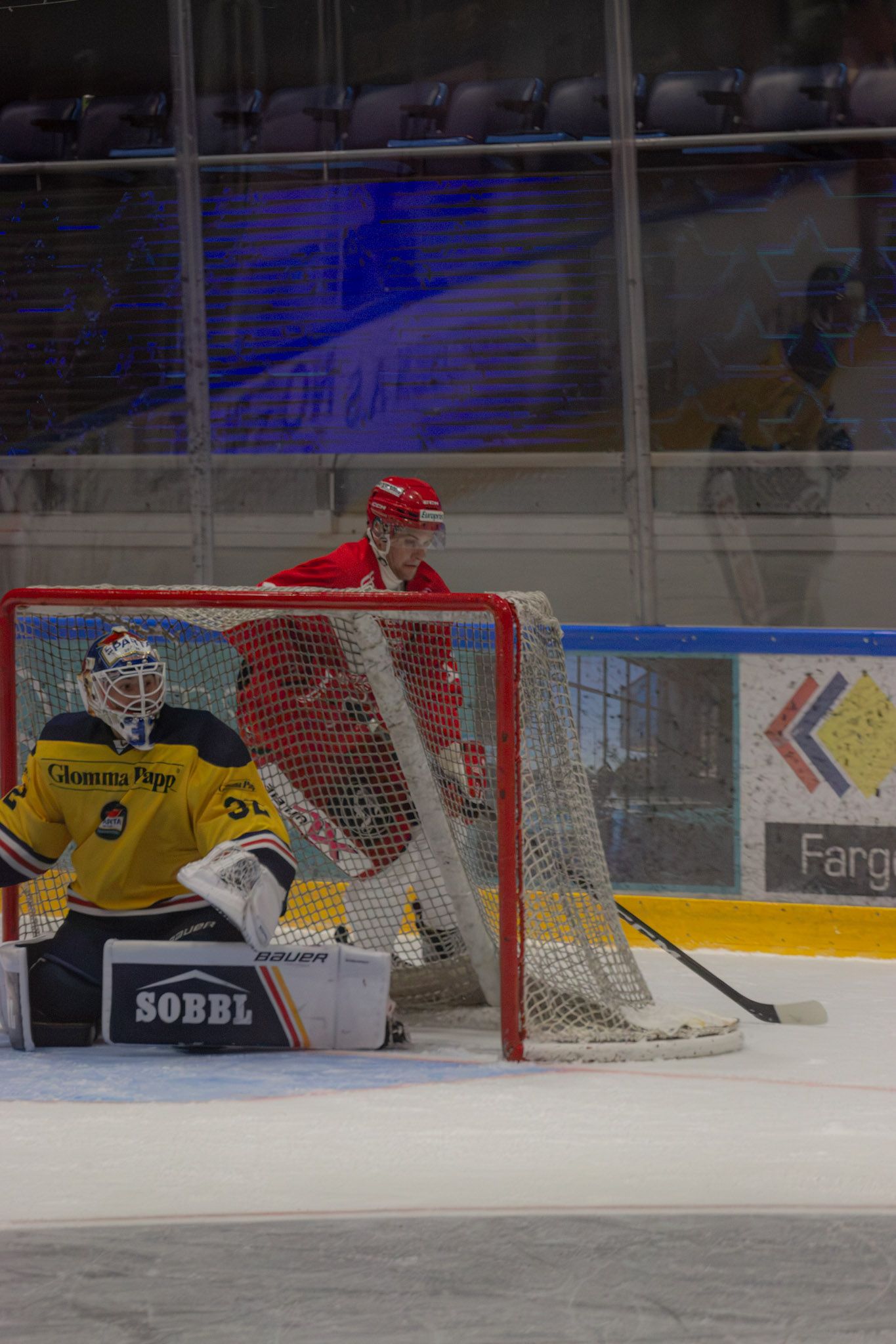 Keeper i gult foran målet, blått glass bak