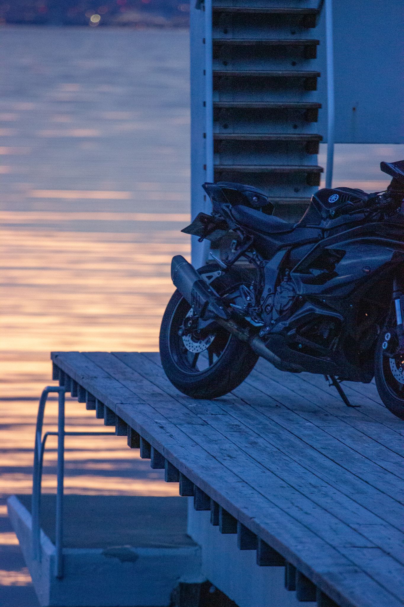 Motorsykkel på brygga mot rosa solnedgang over vannet